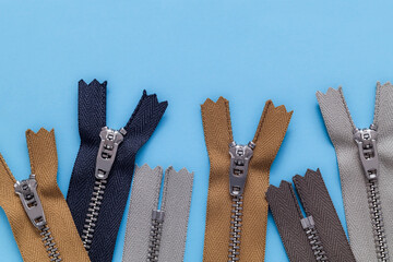 Set of zippers on a blue background. Sewing tools. Top view. Copy space.