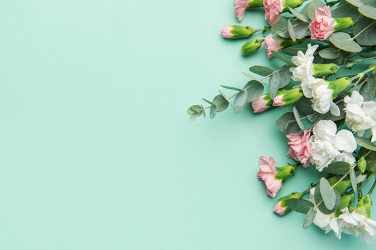A bouquet of white and pink carnations with eucalyptus branches on a soft green background.