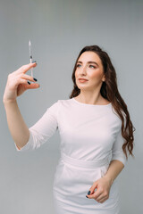young dark-haired curly woman doctor in a white coat holds an insudin syringe for injection in her hands. Cosmetologist in a beauty salon preparing for a beauty procedure