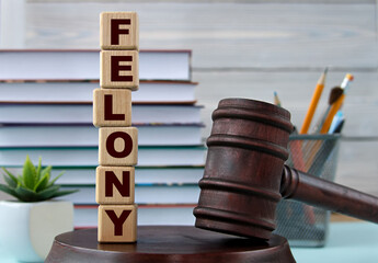 The word FELONY on wooden cubes against the background of the judge's gavel and stand