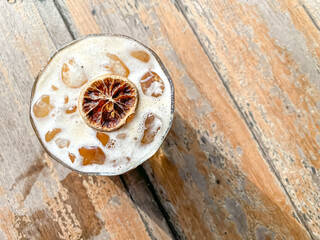 Iced coffee soda drink topped with dried lemon slices on wooden table.  Fresh cold drink during the day or summer. High angle.