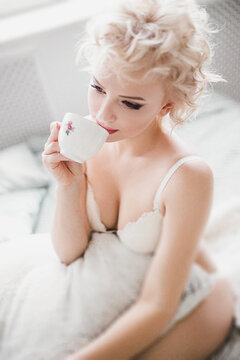 young beautiful slim girl in white underwear with cup coffee