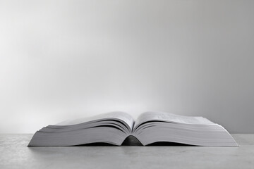 Open Bible on light gray table, space for text. Christian religious book