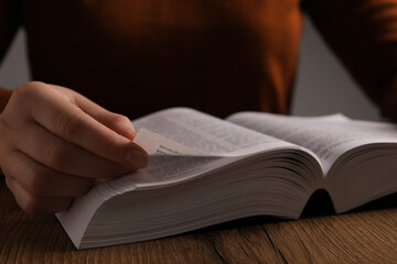 Woman reading Bible at wooden table, closeup