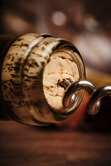 Bottle of wine with a corkscrew on a brown blurred background