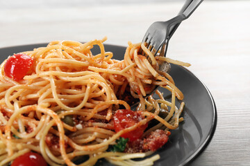 Eating delicious pasta with tomatoes and parmesan cheese at white wooden table, closeup