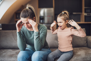 Stressed mother is  feeling desperate because of  screaming  her daughter.