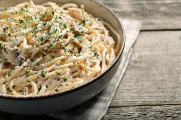 Delicious pasta with mushroom sauce on wooden table, closeup. Space for text