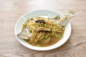 steamed bass fish dressing soybean gravy sauce topping slice ginger and mushroom on plate 
