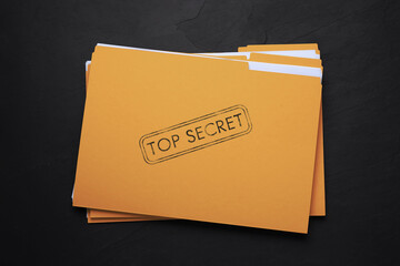 Yellow file with documents and Top Secret stamp on black table, top view