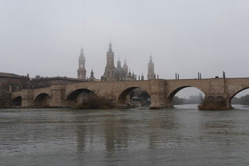 Obraz premium Zaragoza en la niebla del Pilar, el puente de Piedra y el Pila