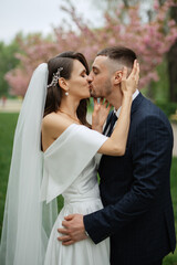 newlyweds walk in the park among cherry blossoms