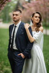 newlyweds walk in the park among cherry blossoms