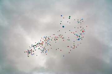 colored Baloons floating away against a stormy grey sky