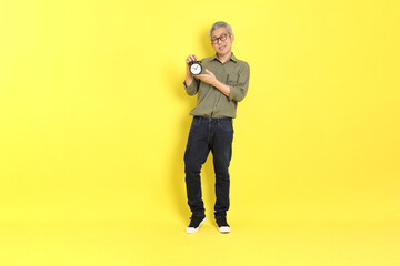 The 40s adult Asian man with casual dressed standing on the yellow background.