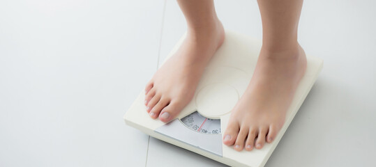 Closeup foot of woman standing on scales measuring for control weight in the room, overweight and...