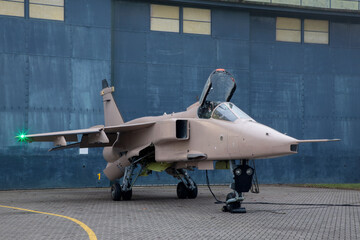 Fighter jet parked outside Hangar with strobe lights on wings