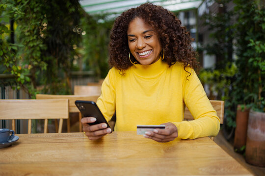Beautiful Brazilian young woman outdoors online shopping with mobile phone