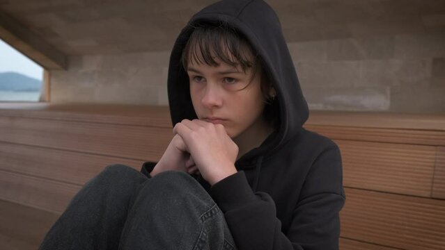 Teenager in depression. A young girl sits at a loss on a park bench. The concept of problems in adolescence.