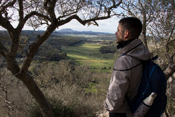 Un joven excursionista contempla el paisaje de la isla de Mallorca, en un soleado dia de invierno.