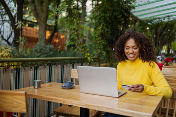 Beautiful Brazilian young woman outdoors with laptop online shopping