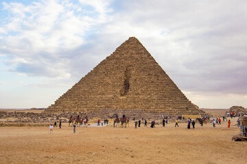 Tourists and locals walking around the Pyramid of Menkaure, archaeological landmark in Giza, Egypt,...