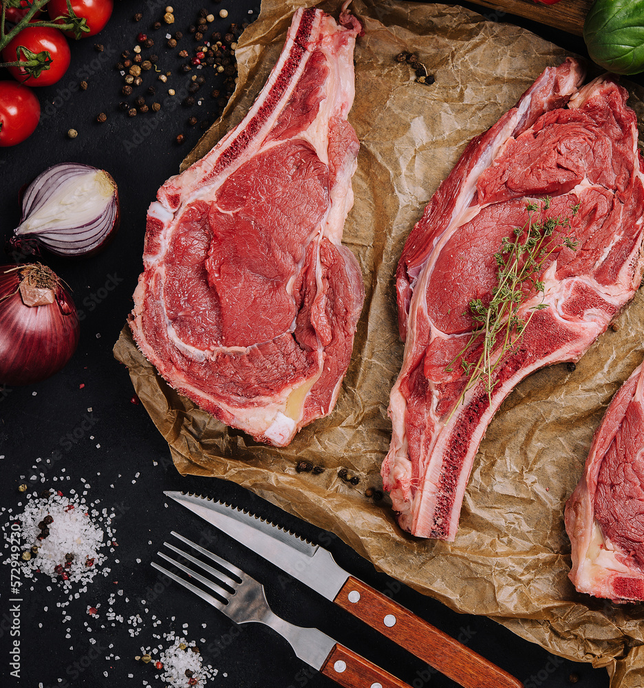 Wall mural Three raw beef steaks on a wooden chopping board, garlic and a sprig of rosemary