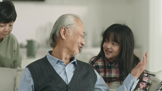 loving asian grandpa and two grandchildren relaxing at home