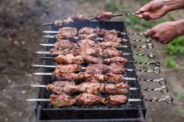flips the fried shish kebab on the grill on the skewers. outdoor