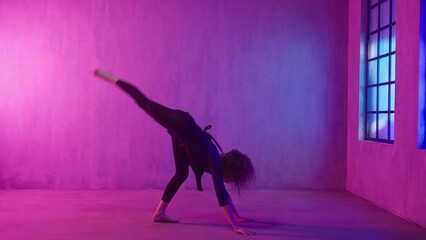 Modern dance girl dancer dancing in neon light doing gymnastic exercises in studio, copy space. - Powered by Adobe