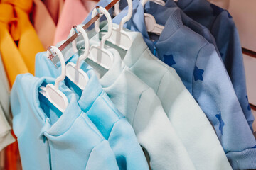 Bright spring jumpsuits for newborns hang on hangers in a children's clothing store