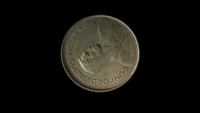 Obverse of Switzerland coin 5 francs with portrait of an alpine herdsman and inscription meaning SWISS FEDERATION, isolated in black background. 4k video
