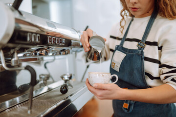 Female barista making coffee in a coffee machine. Food and drink concept.