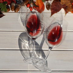 two glasses of red wine on wooden background with autumn leaves