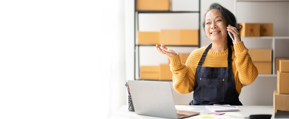 Asian senior small business owner using her smartphone to contact with her customer to get more detail.