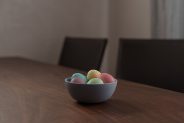 Fototapeta na wymiar Easter eggs in a bowl with napkin on walnut wood table with copy space