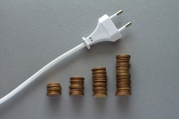 Increasing energy bills costs, stacks of coins with cable with plug moving upwards, electricity price chart concept