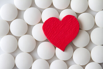 Red heart on background of white pills