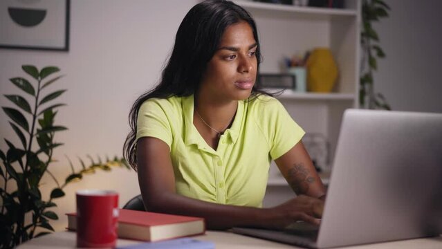 Video Young Indian woman using laptop in home office. Happy girl typing on computer and teleworking. Concentrated people studying for final test. Concept of person preparing for a competitive exam. 