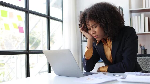 Serious african american businesswoman thinking while working with laptop on office desk. Stress and pressure concept from overwork.