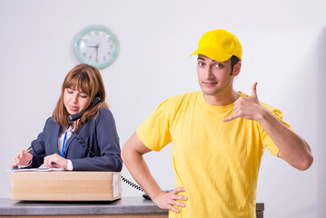 Young male courier delivering box to hotel's reception