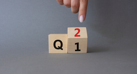 From 1st Quarter to 2nd symbol. Businessman hand points at turned wooden cubes with words 1st...