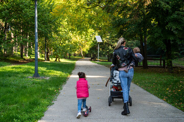 A mother is walking through the park with her children