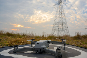 A drone at the power station prepares to fly over an area of electricity with high voltage pylons.