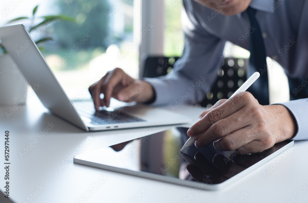 Poster businessman using digital tablet and working on laptop computer on office table. corporate man using