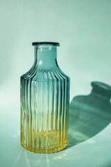 A glass bottle is a flower vase. Shadow. Turquoise background