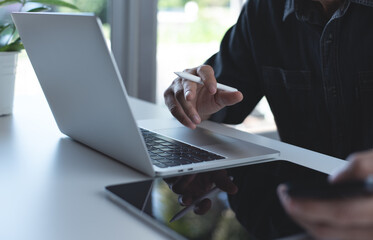 Business man busy working on laptop computer and using mobile phone with digital tablet on table at home office. Working at home, telecommuting