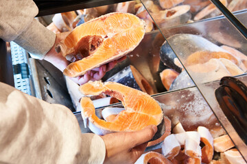 Buyer hand with frozen red salmon fish