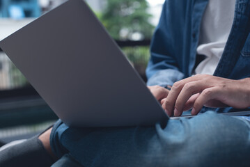 Technology and people lifestyle concept. Man freelancer sitting cross legged using mobile phone and laptop computer outdoors. Man online working and surfing the internet, close up