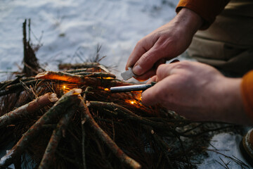 Male hand starts fire with magnesium fire steel, fire striker.